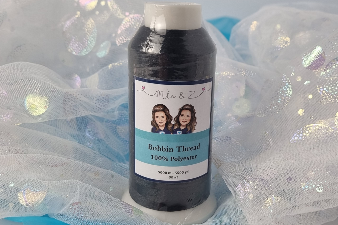Spool of black thread with a label on a glittery white fabric background
