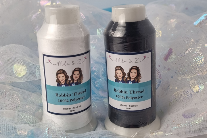 Two spools of 'Bobbin Thread' by 'Mila & Z' (black & white) on a glittery background